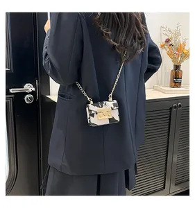 Detailed back view of a mini cow print crossbody bag with golden chain on a model