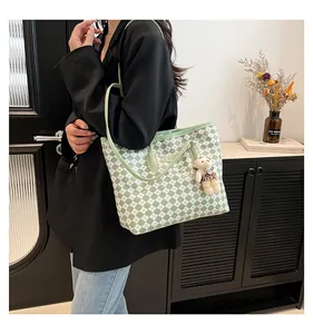 Detail of green and white checkerboard tote bag with cute beige bear charm on strap