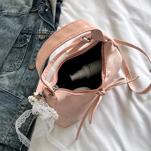 Roze tas interieur toont opslagcapaciteit met kanten details en een parelhanger