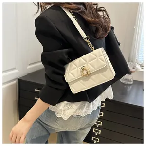 Détail d'un sac bandoulière blanc matelassé avec fermoir doré et bandoulière en chaîne