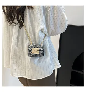 Mini leopard print crossbody bag with gold chain strap worn by a model in lifestyle view