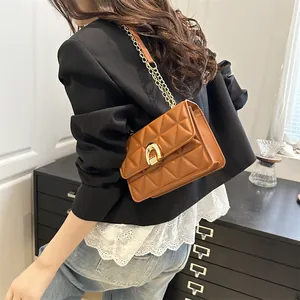 Sac à bandoulière matelassé marron avec chaîne dorée porté par un mannequin en intérieur