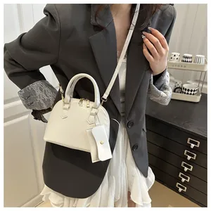 Detailed view of a white shell handbag with a matching mini pouch on a grey blazer
