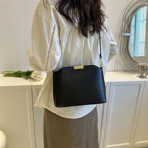 Minimalist black leather crossbody bucket bag with gold accents shown on a model back view