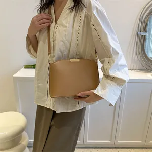 Minimalist khaki shell-shaped crossbody bag with gold metal trim and leather shoulder strap