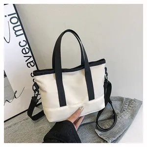 Minimalist cream canvas tote bag with black strap details on casual denim surface