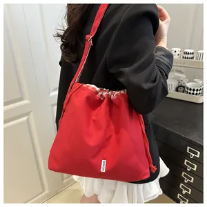 Detail of red canvas drawstring bag showing the adjustable strap and fashion label on shoulder