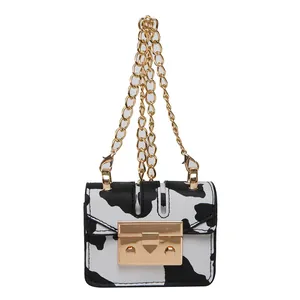 Chic mini crossbody bag with black and white cow print and gold chain strap