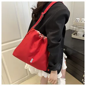 Detail of red canvas tote with plaid drawstring closure and adjustable wide strap