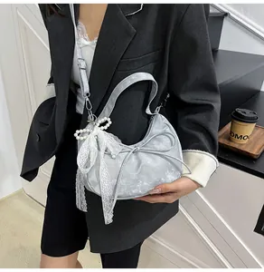 Detail van de zilveren halve maan tas met kanten strik en parelhanger accessoires