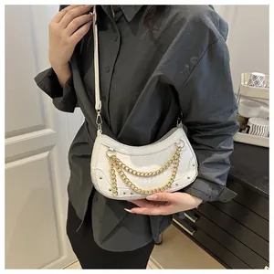 Detail van witte halfmaanvormige tas met krokodillenreliëf en gouden ketting