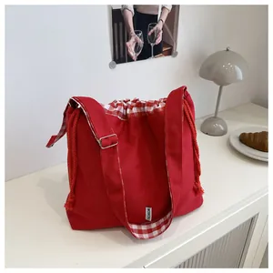 Detail of red canvas tote bag with adjustable strap and checkered drawstring closure