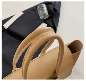 Detailed shot of reinforced double round handles and fine stitching on a beige leather tote