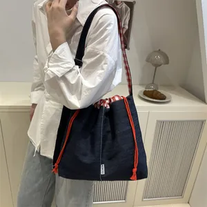 Denim crossbody bag with red plaid lining and adjustable straps for casual style