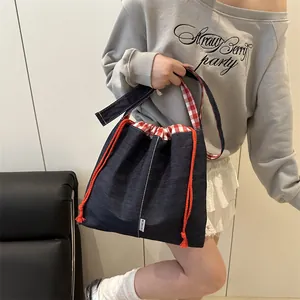 Denim drawstring bucket bag with red checkered lining and adjustable strap for women