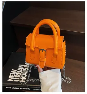 Detail of orange mini square bag with silver D-buckle and metallic chain strap