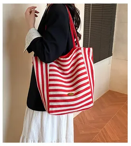 Détail du sac cabas en toile à rayures rouges et blanches avec étiquette en métal