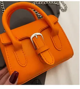 Detail der orangefarbenen Mini-Handtasche aus Kunstleder mit Silberschnalle