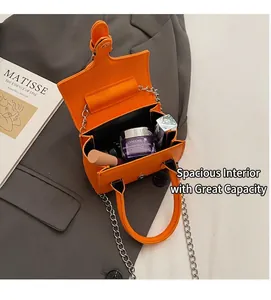 Innenansicht der leuchtend orangen Tasche mit Silberkette auf grauem Blazer
