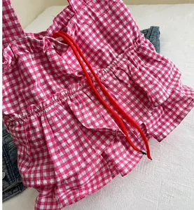 Dettaglio del tessuto a quadri rosa con bordi a balze e cordoncino decorativo rosso
