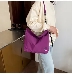 Detail view of purple waterproof nylon crossbody bag with adjustable braided rope strap