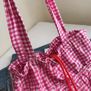 Dettaglio della borsa tote vichy rosa con trama del tessuto e coulisse rossa
