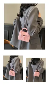 Detail of pink mini leather handbag featuring top handle and sleek metal chain strap