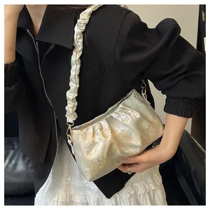 Detalle de tela jacquard floral y asa scrunchie en el bolso de hombro color crema