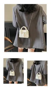 Detailed view of white mini square bag with silver chain strap and top handles