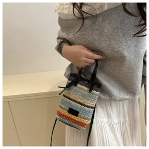 Mini sac seau tissé multicolore porté par un mannequin avec bandoulière et poignée