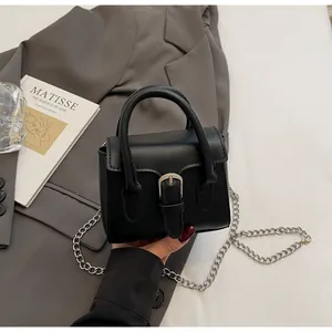 Detail of a black leather mini square bag with silver buckle and metal chain strap