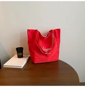 Détail d'un sac cabas en toile rouge avec lettrage merci blanc sur une table en bois