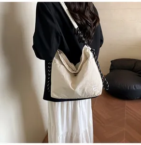 Detail of a beige nylon crossbody bag with braided rope strap and logo embroidery