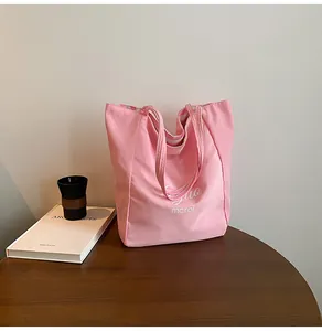 Détail d'un sac cabas en toile rayée rose avec logo blanc sur une table en bois foncé