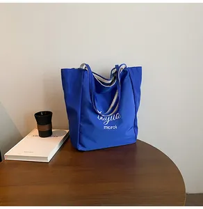 Détail du sac cabas en toile bleue sur table en bois avec doublure intérieure rayée