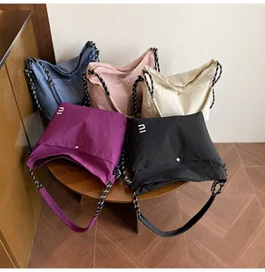Détail de sacs bandoulière en nylon léger en cinq couleurs sur une table en bois