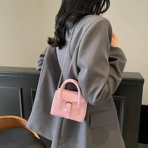 Pink minimalist retro square handbag with silver chain strap worn over a grey blazer