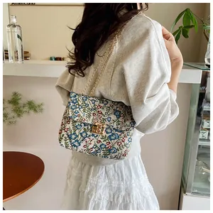 Detail view of the floral embroidered envelope bag with elegant golden chain strap