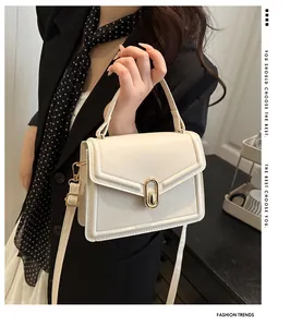 Close-up of cream PU leather handbag with gold oval twist lock and adjustable strap