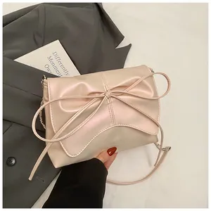 Detailopname van parelroze crossbodytas met grote strik en elegante schouderband