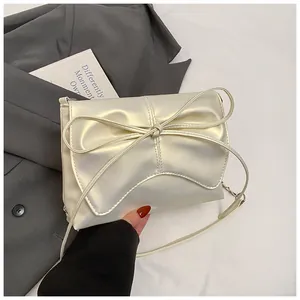 Close-up van de parelwitte geplooide tas met een elegante strik en lederen textuur