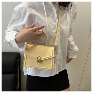 Detalle del bolso de cuero amarillo claro con cierre de giro dorado y costuras finas