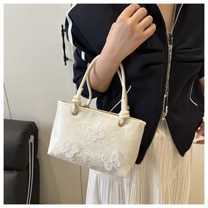 Close-up of white lace bucket bag with detailed 3D butterfly embroidery and woven strap