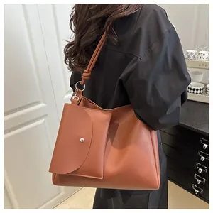 Detail of caramel faux leather bucket bag with a matching pouch and metal ring shoulder strap