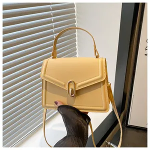 Détail du sac à main en cuir jaune clair avec fermoir ovale doré et bandoulière