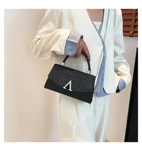 Détail de la surface en paillettes et boucle en V argentée sur le sac de soirée noir