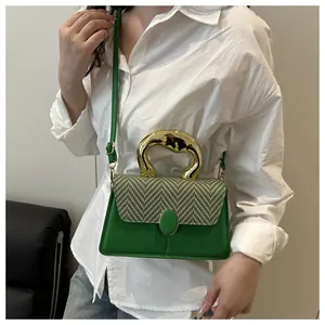 Detail of green woven bag featuring a bold irregular gold mirror metal handle and strap