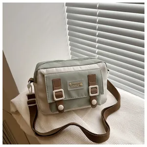 Detail van grijsgroene canvas crossbodytas met leren riemen en decoratieve gesp