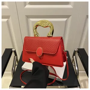 Detail of red textured lady bag with thick gold sculptural handle and woven pattern cover