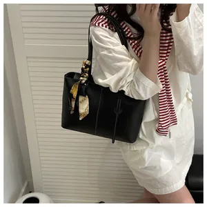 Detail of black leather tote bag featuring contrast white stitching and silk scarf wrap